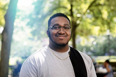 Image of man with glasses, outdoors under trees.