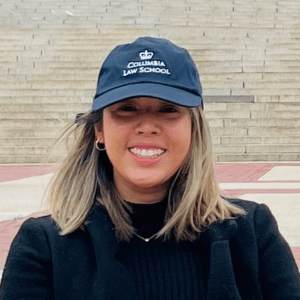 Image of a woman smiling outdoors, wearing a Columbia Law School baseball cap.