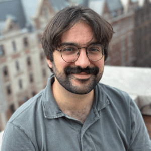 Man in glasses, with beard, smiling from Columbia's campus.