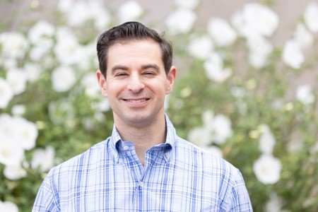 Portrait of smiling man, standing outside.