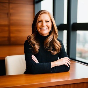 Woman, with folded arms, smiling from desk.