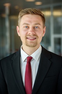 Portait of man in suit and tie, smiling.