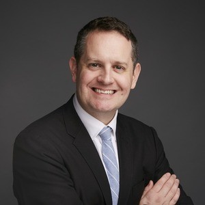Man in business attire, arms crossed over chest.
