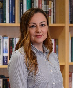 Portrait of a smiling woman in front of bookshelves.