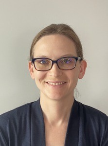 Portrait of smiling woman with glasses in professional attire.