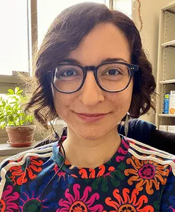 Portrait of smiling woman with glasses, in her office. 