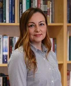Portrait of a smiling woman in front of bookshelves.